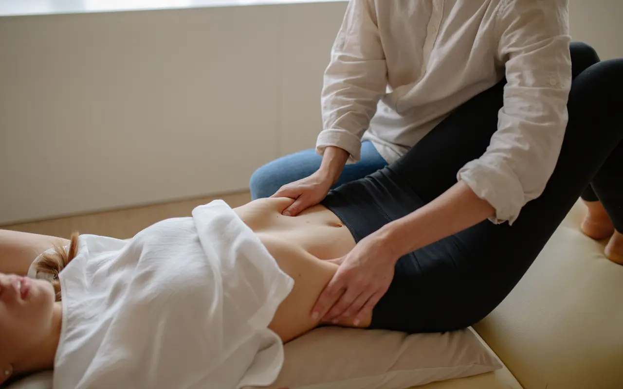 Fisioterapeuta a trabalhar a região abdominal de uma utente deitada